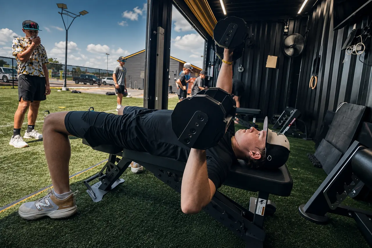 Athlete performing a dumbbell bench press inside the FLXPOD